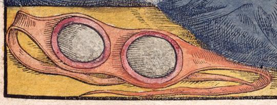 Image of goggles with glasses set in a band that can be tied around the head, detail of a woodcut from the 16th century.